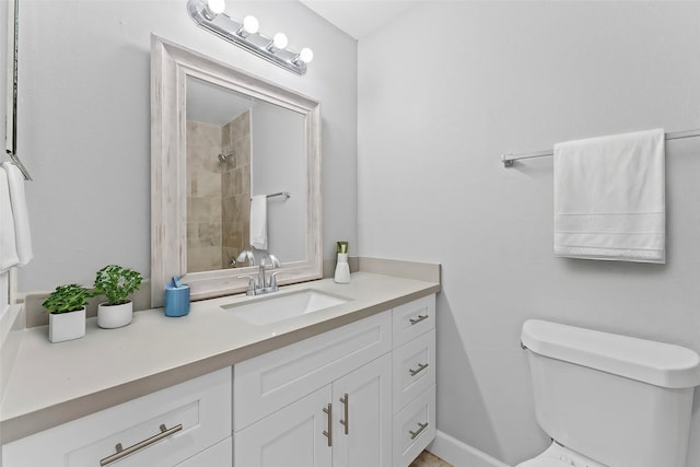 bathroom with tiled shower, vanity, and toilet