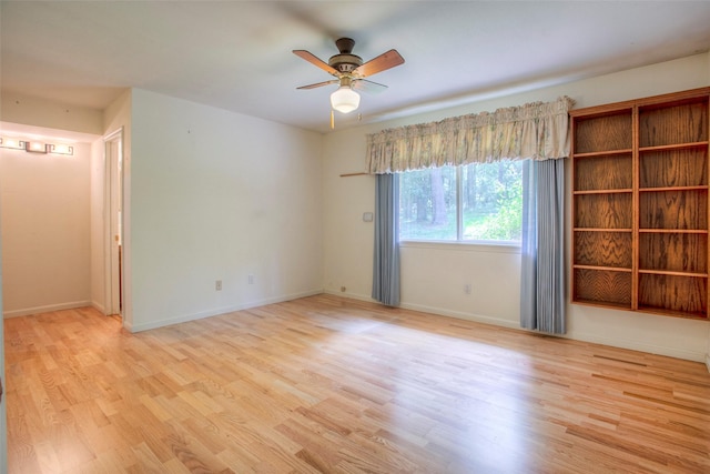 empty room with light wood-type flooring, a ceiling fan, and baseboards