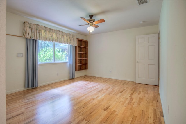 empty room featuring visible vents, ceiling fan, light wood-style flooring, and baseboards