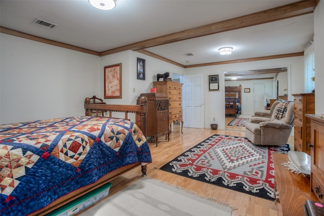 bedroom featuring light wood-style floors, visible vents, and crown molding