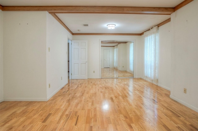 unfurnished room featuring beamed ceiling, ornamental molding, and light hardwood / wood-style flooring