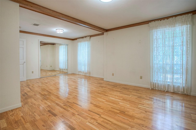 spare room featuring beam ceiling, light hardwood / wood-style floors, and ornamental molding