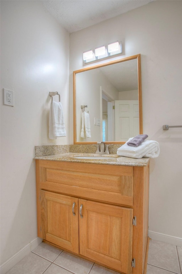 bathroom with tile patterned flooring, baseboards, and vanity