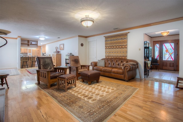 living room with crown molding, a textured ceiling, and hardwood / wood-style flooring