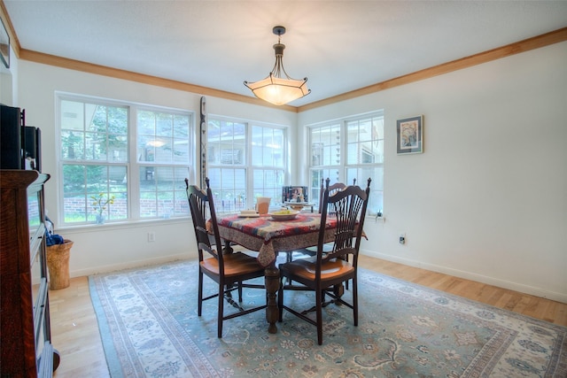 dining area with crown molding, light wood-style flooring, and baseboards