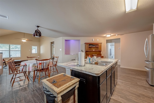 kitchen featuring stainless steel fridge, sink, an island with sink, and hardwood / wood-style floors