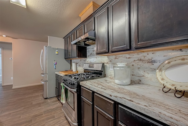 kitchen featuring dark brown cabinetry, stainless steel appliances, light hardwood / wood-style floors, and backsplash