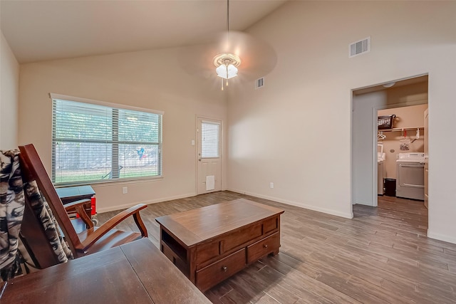 interior space featuring ceiling fan, high vaulted ceiling, light hardwood / wood-style floors, and washer / dryer