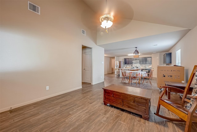 living room with hardwood / wood-style flooring, high vaulted ceiling, and ceiling fan