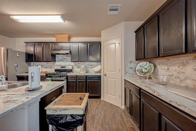 kitchen with tasteful backsplash, dark hardwood / wood-style flooring, dark brown cabinets, and appliances with stainless steel finishes