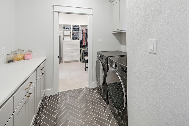 clothes washing area featuring cabinets and independent washer and dryer