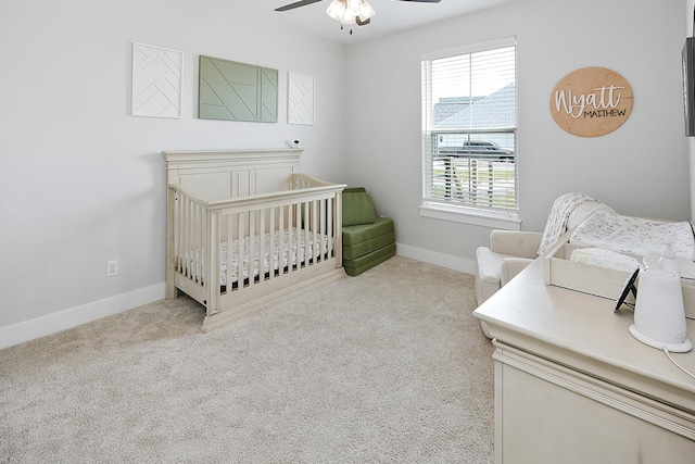 bedroom with ceiling fan, light carpet, and a crib