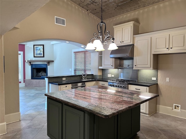 kitchen with stainless steel appliances, decorative light fixtures, white cabinets, a chandelier, and a kitchen island