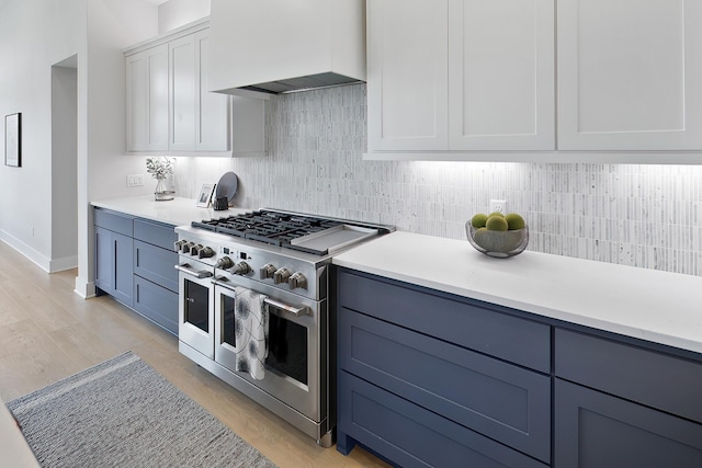 kitchen featuring custom range hood, white cabinetry, range with two ovens, and light hardwood / wood-style flooring