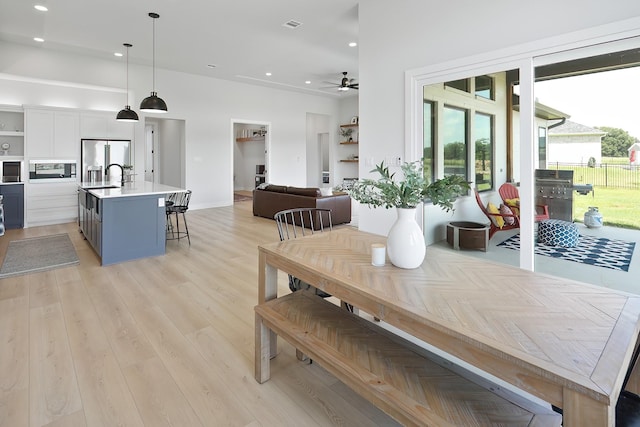 dining space featuring ceiling fan, sink, and light hardwood / wood-style floors