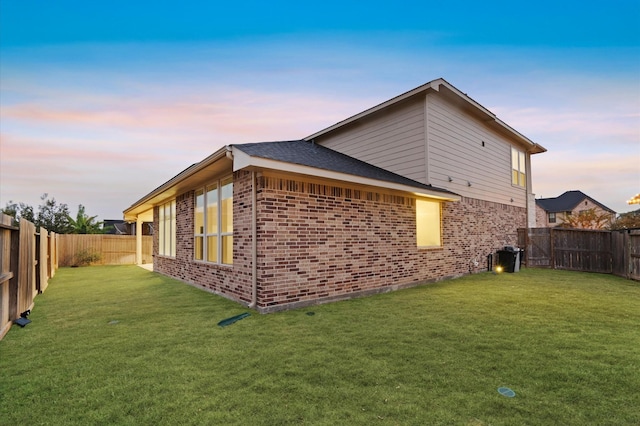 view of home's exterior with brick siding, a yard, and a fenced backyard