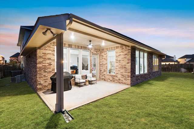 back of property with brick siding, a lawn, a patio area, and fence