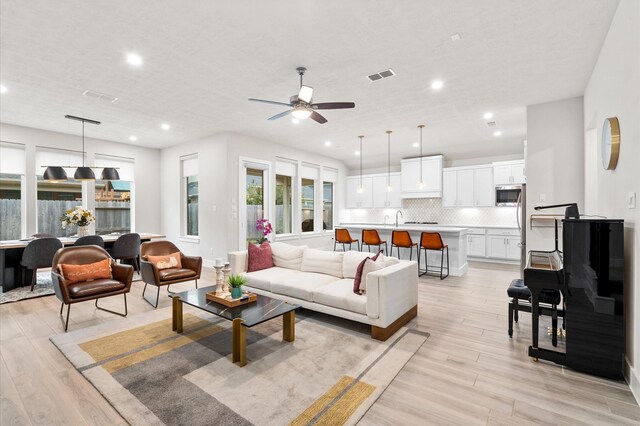 living room featuring light wood-style floors, visible vents, a ceiling fan, and recessed lighting