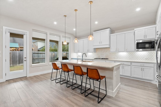 kitchen featuring a sink, a center island with sink, stainless steel appliances, and decorative backsplash