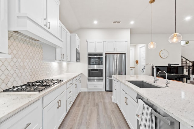 kitchen with stainless steel appliances, a sink, visible vents, and white cabinetry