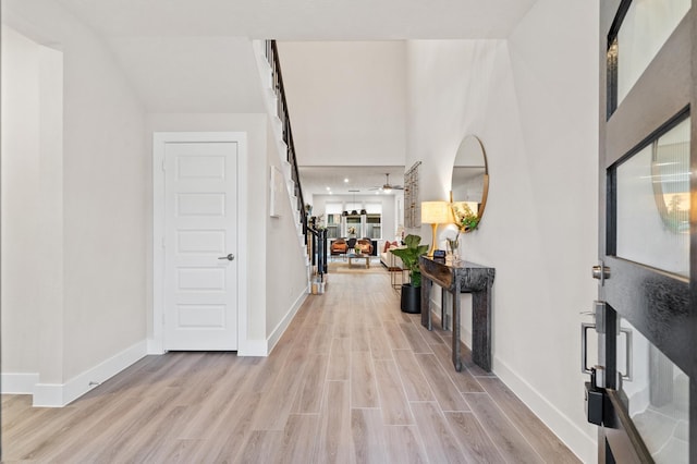 entrance foyer featuring light wood-type flooring, baseboards, stairway, and ceiling fan