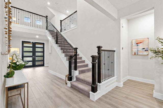 entryway with a high ceiling, baseboards, wood finished floors, and french doors