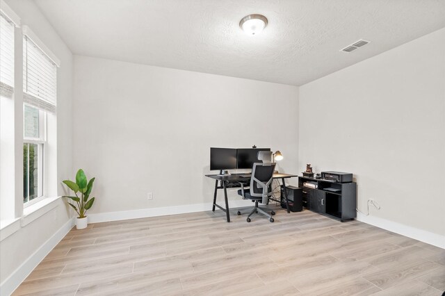 office area featuring visible vents, a textured ceiling, baseboards, and wood finished floors