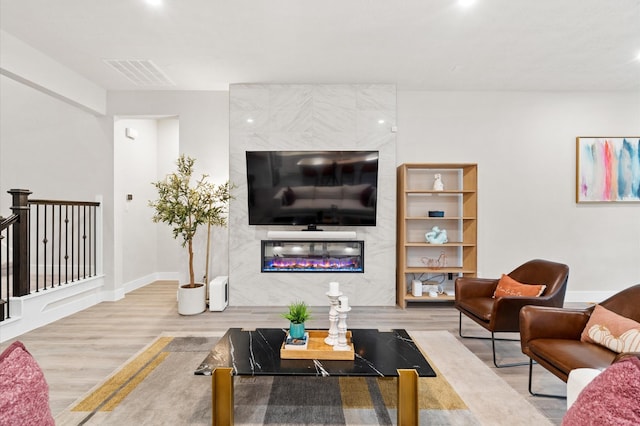 living area featuring a high end fireplace, visible vents, baseboards, and wood finished floors