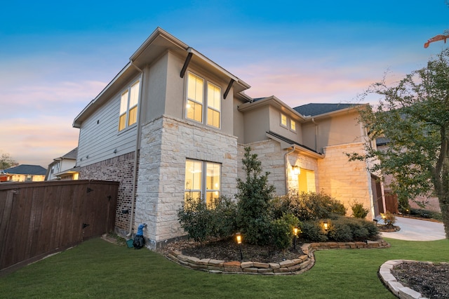 view of property exterior featuring stone siding, a lawn, and stucco siding