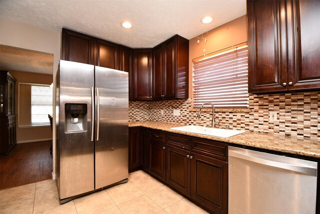 kitchen featuring sink, stainless steel appliances, light stone counters, decorative backsplash, and light tile patterned floors