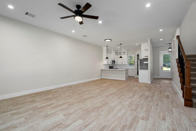 unfurnished living room featuring ceiling fan and light hardwood / wood-style floors