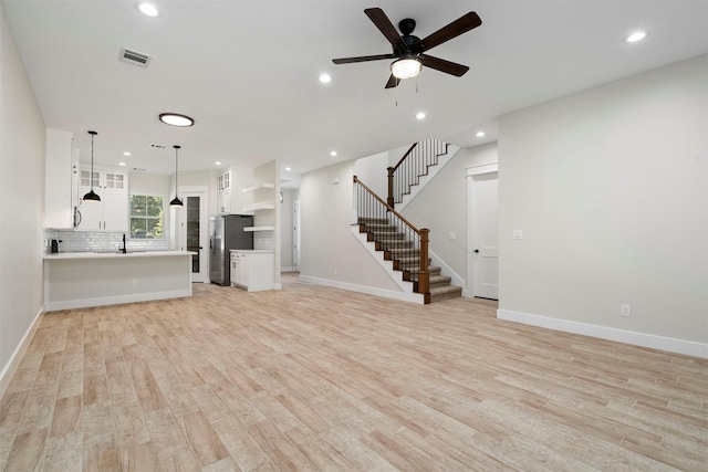 unfurnished living room with light hardwood / wood-style floors, ceiling fan, and sink