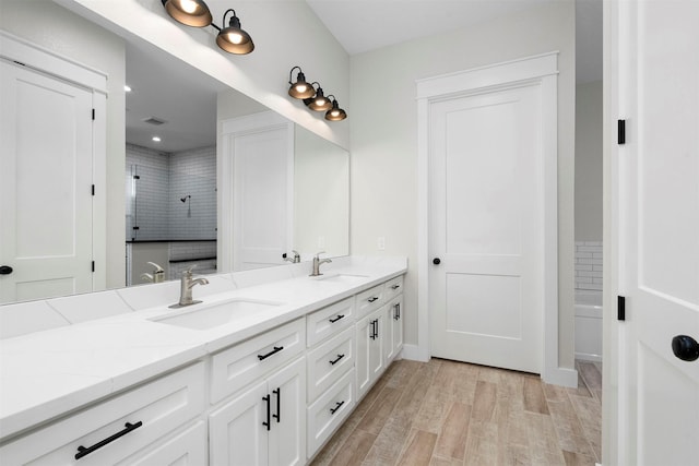 bathroom with wood-type flooring, vanity, and a tile shower