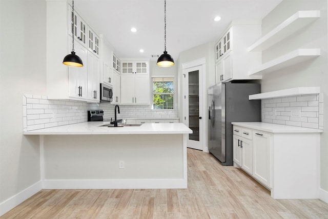 kitchen featuring pendant lighting, white cabinets, kitchen peninsula, and appliances with stainless steel finishes