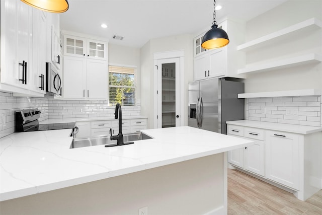 kitchen featuring kitchen peninsula, white cabinetry, hanging light fixtures, and appliances with stainless steel finishes