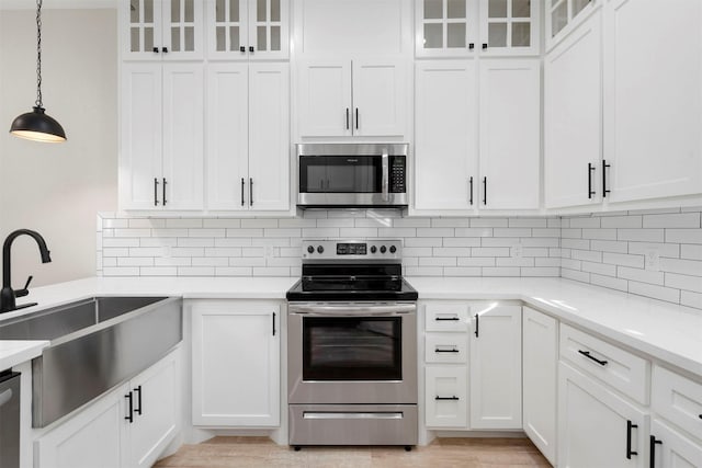 kitchen with white cabinets, pendant lighting, stainless steel appliances, and sink