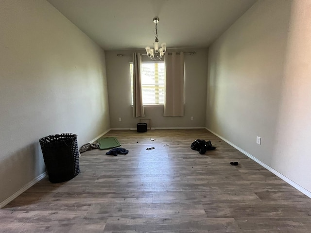 unfurnished room with wood-type flooring and an inviting chandelier