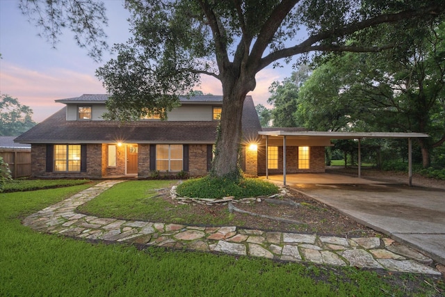 view of front of property featuring an attached carport, brick siding, a lawn, and driveway