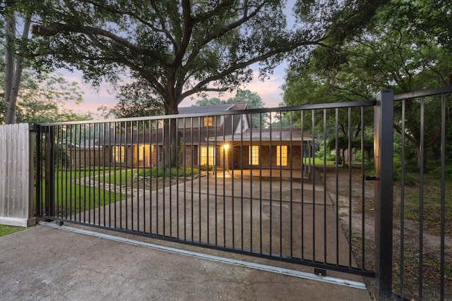 gate at dusk with fence and a lawn