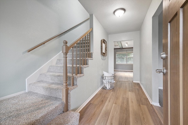 entrance foyer featuring light wood finished floors, baseboards, and a textured ceiling