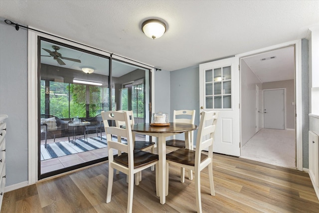 dining room with a ceiling fan, visible vents, a textured ceiling, and wood finished floors