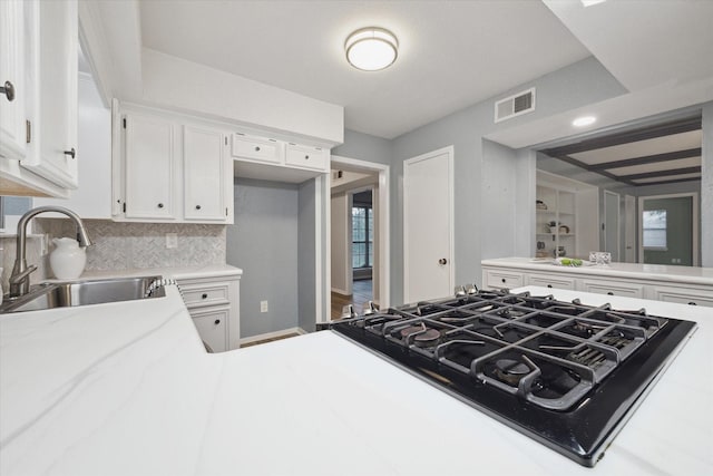 kitchen with gas cooktop, a sink, visible vents, white cabinets, and light countertops