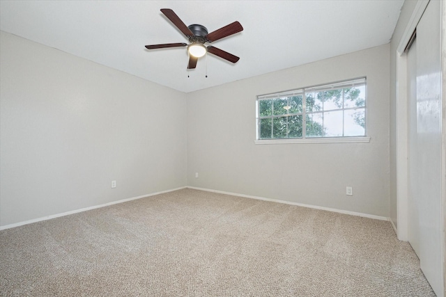 carpeted spare room featuring ceiling fan and baseboards