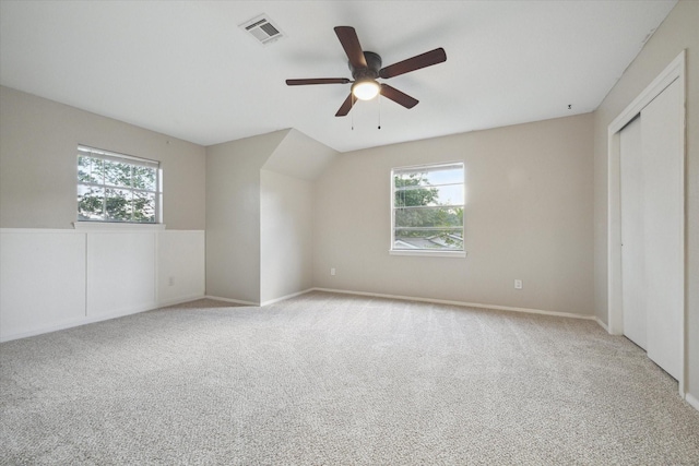 unfurnished bedroom featuring light colored carpet, visible vents, ceiling fan, and multiple windows