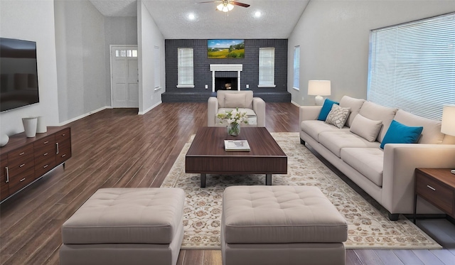 living room featuring a brick fireplace, a textured ceiling, ceiling fan, high vaulted ceiling, and hardwood / wood-style floors