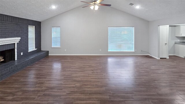 unfurnished living room with a brick fireplace, dark hardwood / wood-style floors, a textured ceiling, and vaulted ceiling