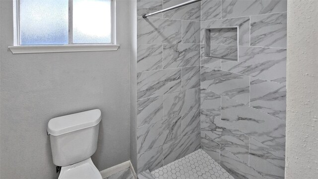 bathroom featuring toilet and a tile shower