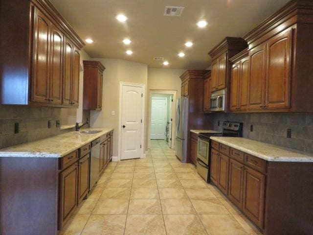 kitchen with backsplash, sink, light tile patterned floors, and stainless steel appliances