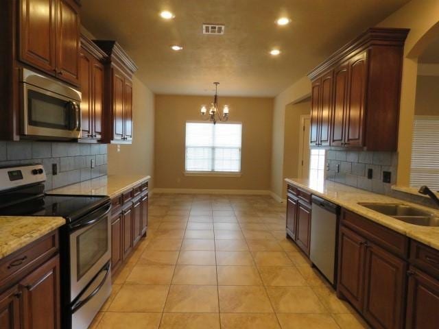 kitchen with sink, light tile patterned floors, appliances with stainless steel finishes, tasteful backsplash, and a notable chandelier