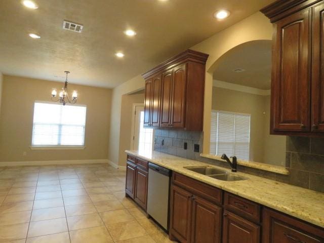 kitchen featuring tasteful backsplash, stainless steel dishwasher, sink, light tile patterned floors, and a chandelier